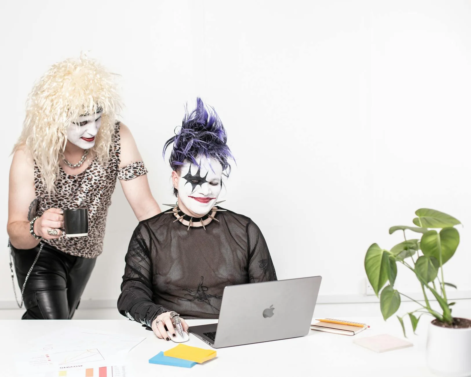 smiling people in costumes standing and sitting with laptop
