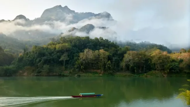 misty morning in nong khiaw with boat on river